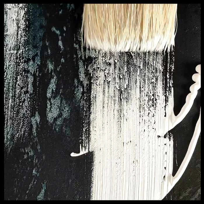 “Close-up view of paintbrush tip blending white paint on a textured black canvas, creating subtle abstract strokes and organic textures.