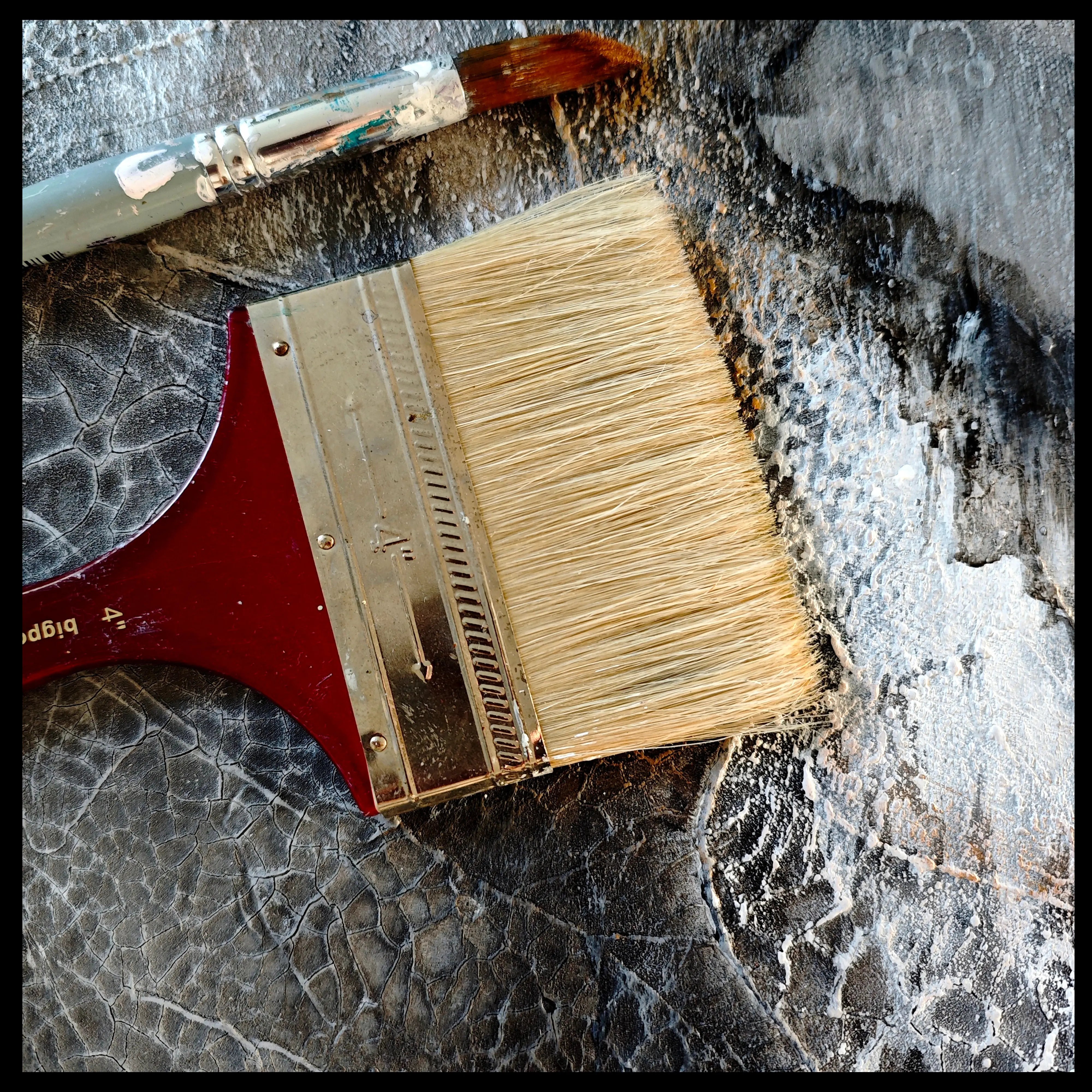 Close up on a textured painting in black and white and brushes lying on the canvas in an art studio. 