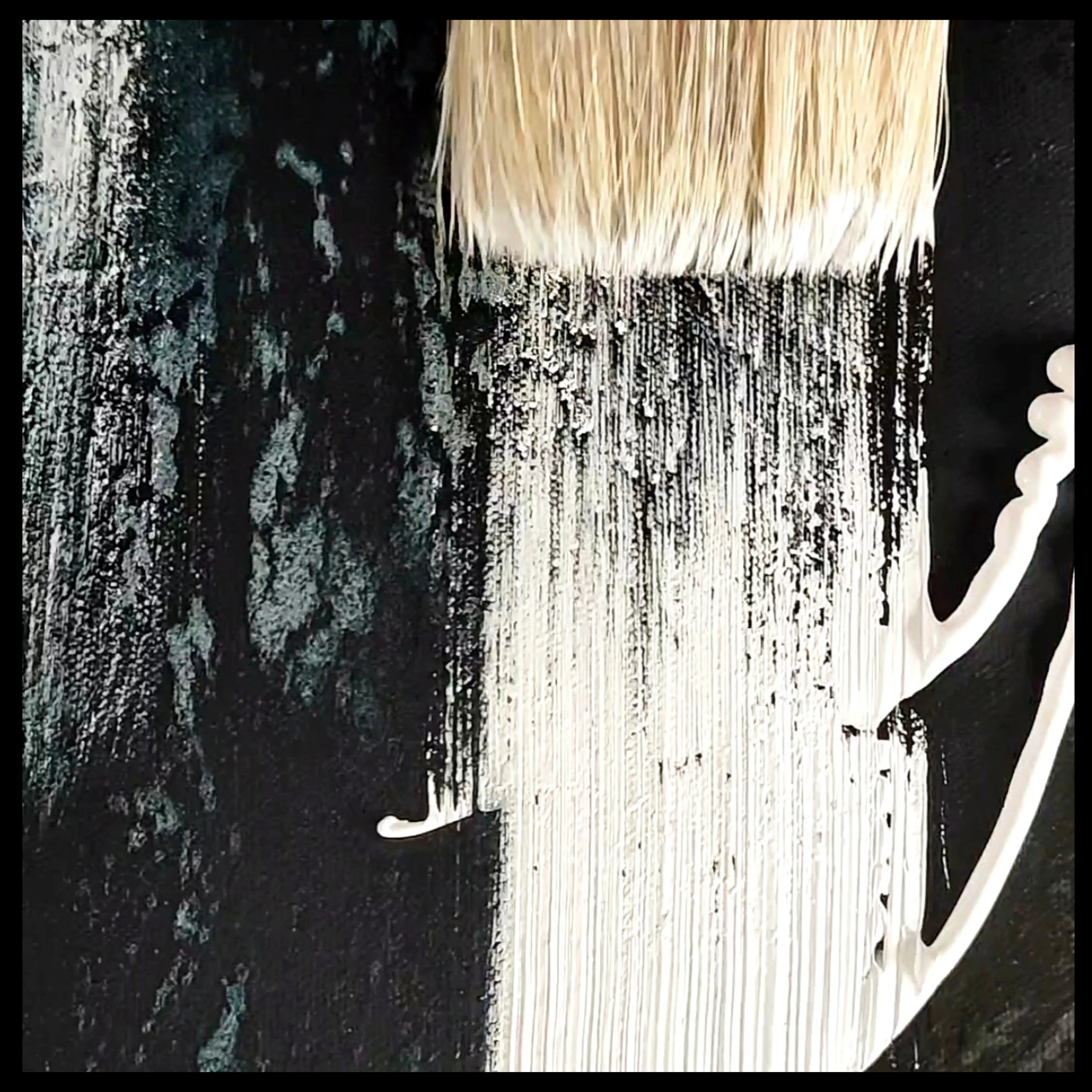 Close up on a black and white minimalist painting and a brush working on canvas in the artist studio of Anez Ka, contemporary artist. 