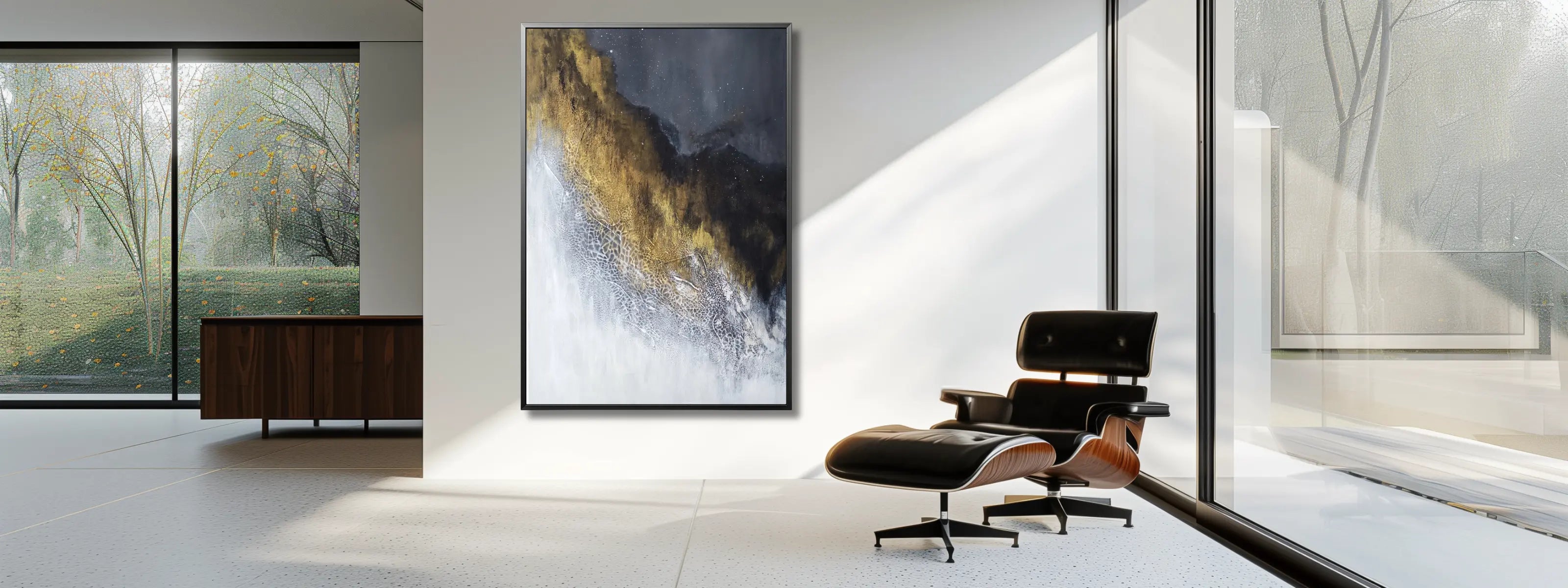 Spacious minimalist living room with a leather designer armchair and a bespoke luxury wall art in gold, black and white in a silver frame on a white wall. 